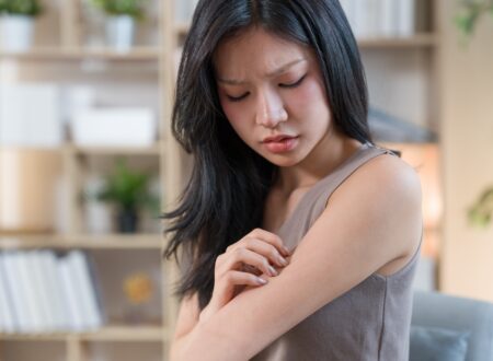 Woman examining dry skin in a bathroom affected by hard water while using a sensitive skin cleanser, active skincare, and the best niacinamide serum.