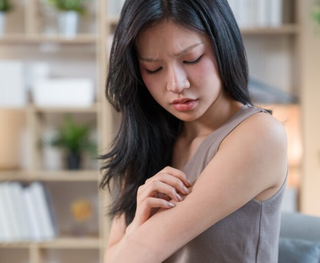 Woman examining dry skin in a bathroom affected by hard water while using a sensitive skin cleanser, active skincare, and the best niacinamide serum.