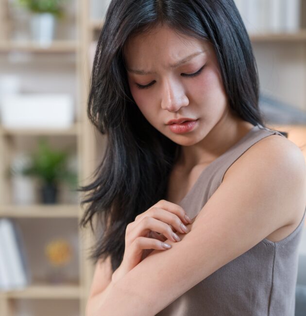 Woman examining dry skin in a bathroom affected by hard water while using a sensitive skin cleanser, active skincare, and the best niacinamide serum.