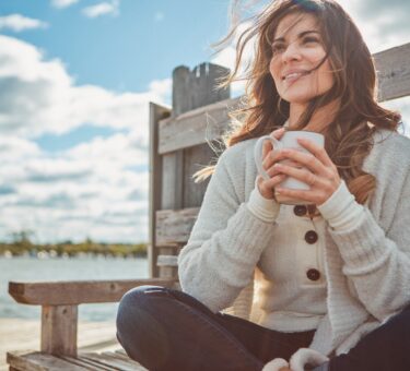 Confident woman smiling outdoors after a smile makeover, highlighting orthodontic treatments for adults and family orthodontic care benefits.