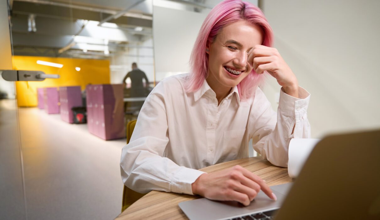 Confident professional woman smiling at work while considering adult braces, orthodontics for adults, and straightening teeth without braces.