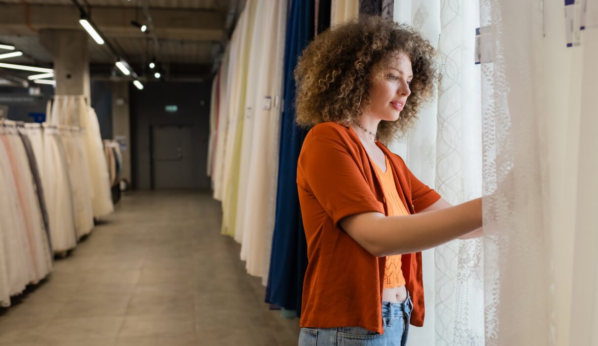 Homeowner choosing custom curtains with an Australian curtain manufacturer, exploring sustainable curtain options and premium fabric samples.