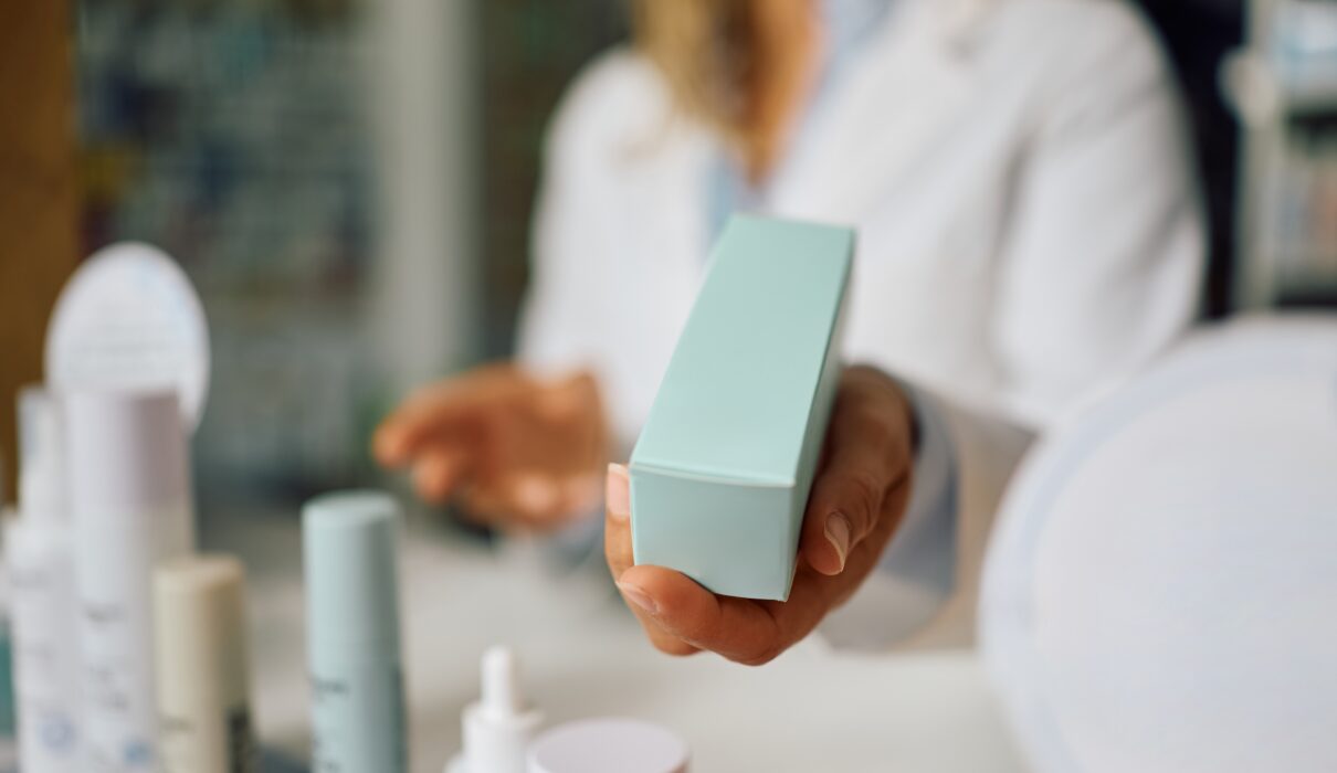 Woman comparing active skincare products, retinal cream, and acne prone skincare products while deciding whether expensive skincare is worth the price.