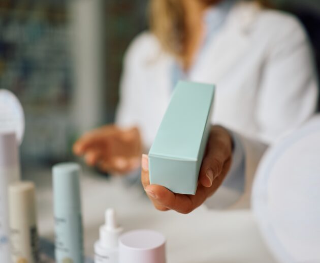 Woman comparing active skincare products, retinal cream, and acne prone skincare products while deciding whether expensive skincare is worth the price.