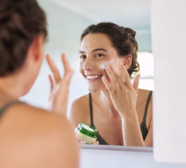 Woman applying an anti ageing serum after using a sensitive skin cleanser as part of a simple active skincare routine.