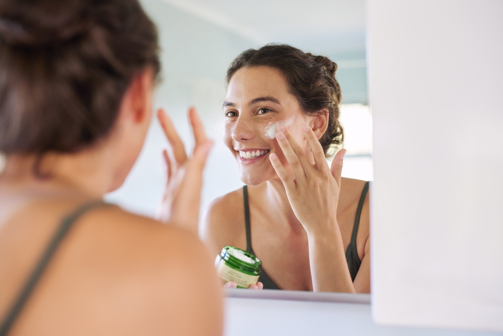 Woman applying an anti ageing serum after using a sensitive skin cleanser as part of a simple active skincare routine.